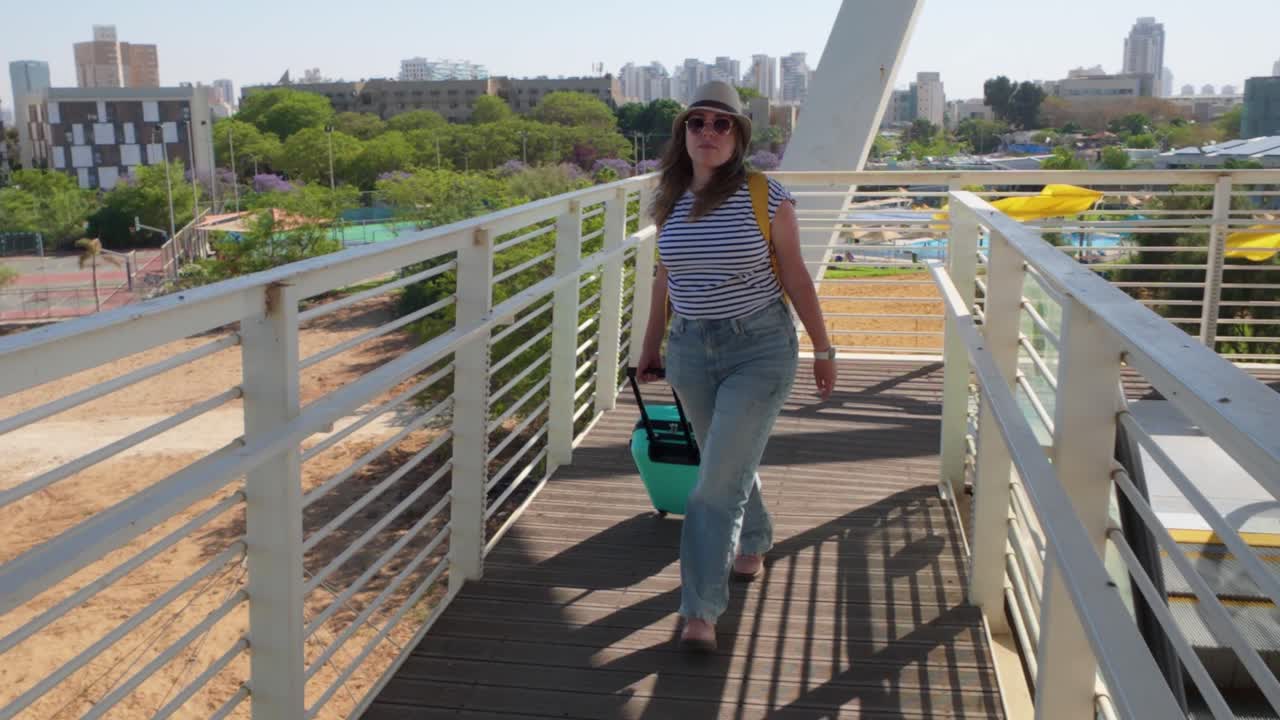 The traveler crosses a pedestrian bridge in the terminal, heading toward her gate.