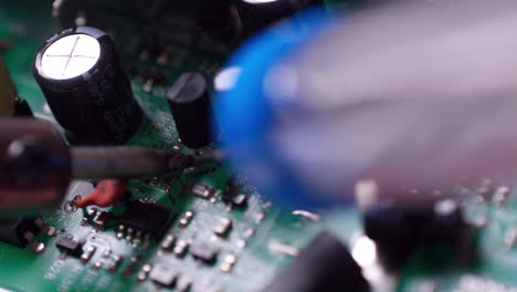 electronic printed circuit board or pcb with transistors and capacitors under repair using soldering iron and lead