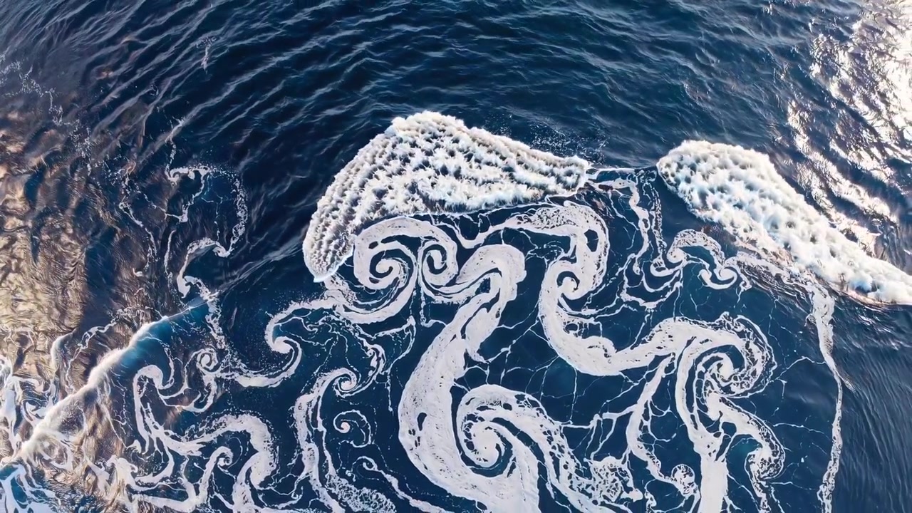 Aerial View of Ocean Waves Creating Intricate Foam Patterns