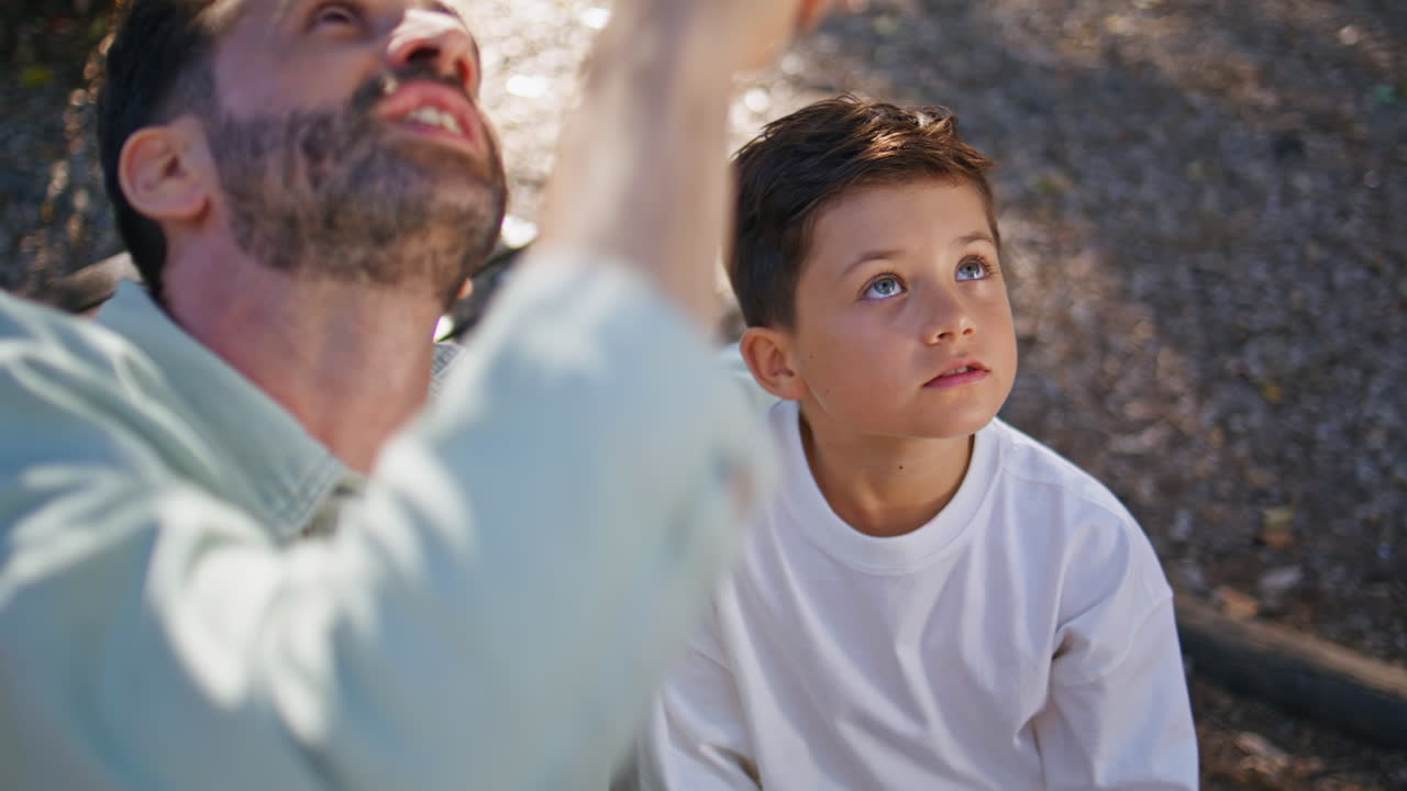 Child dad sitting bench looking distance enjoy conversation at forest closeup