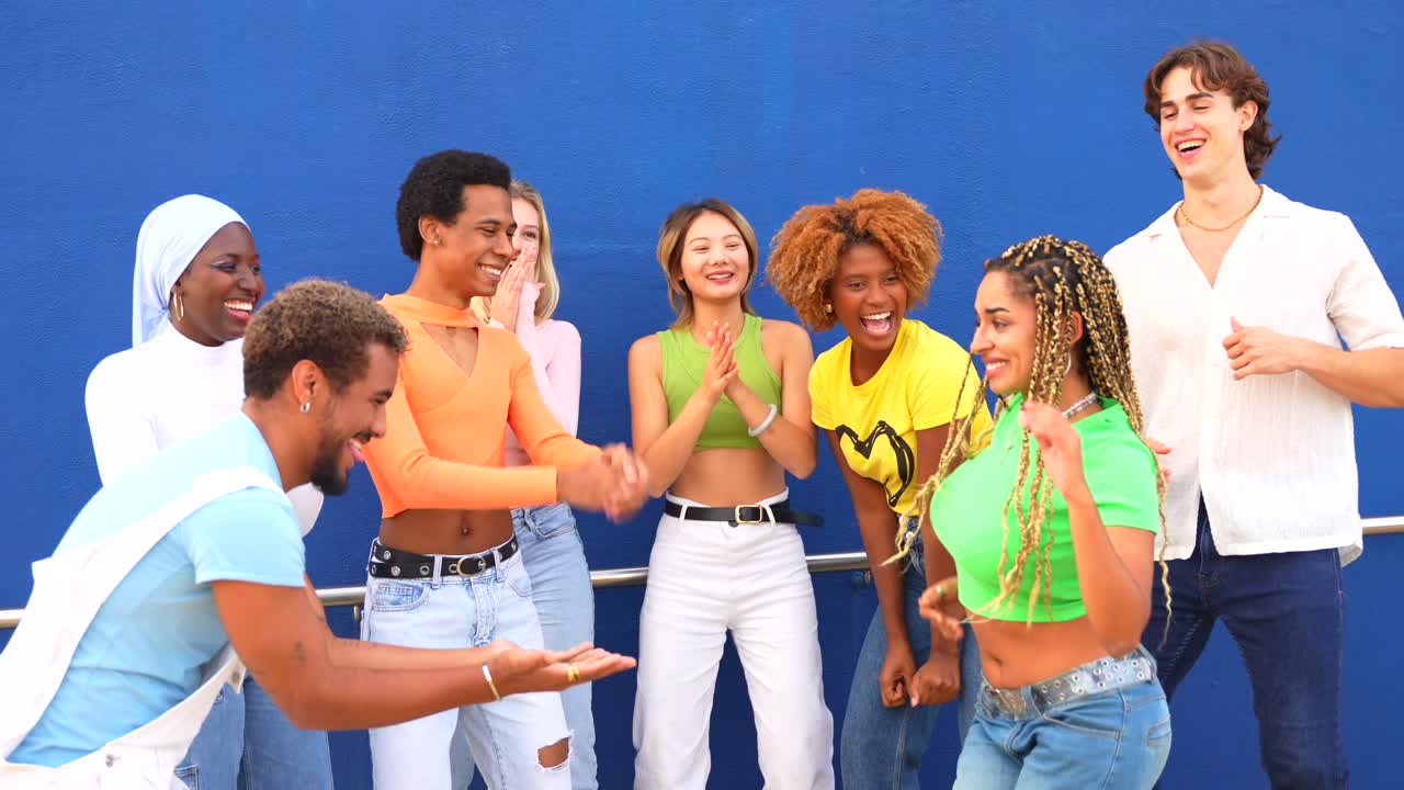 A group of young, diverse friends celebrate and enjoy each other's company against a vibrant blue backdrop