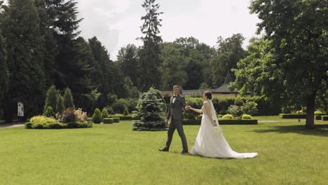 Lovely-newlyweds-caucasian-bride-groom-walking-in-park,-holding-hands,-wedding-couple-family