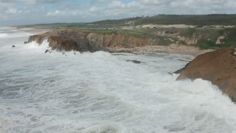 flying towards waves from a wild sea slamming on rocky cliffs