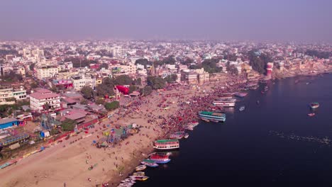 mela with tourist boats are parked on ganga river port and varanasi city at kashi, banaras, uttar pradesh, india. day time, pan shot, drone shot, 4k.