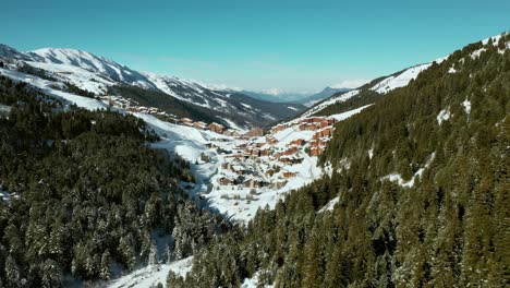 Aerial:-Val-Thorens-ski-resort-on-mountainside,-French-Alps-in-winter-snow