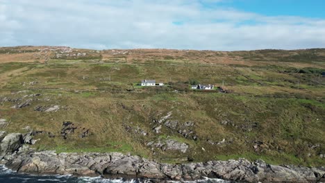 Aerial reveal, rustic cottages nestled on Connemara’s rocky coast in County Galway, Ireland, framed by rugged moorland and sweeping Atlantic shoreline