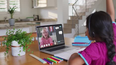 Schoolgirl-using-laptop-for-online-lesson-at-home,-with-her-colleague-and-web-chat-on-screen