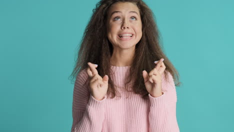 caucasian curly haired woman crossing fingers in front of the camera.