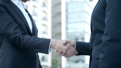 two businesswomen shaking hands on street