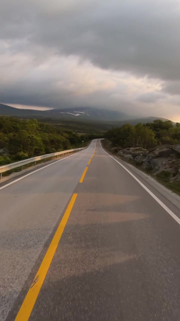 Strada deserta nelle montagne norvegesi all'alba, paesaggio di viaggio verticale