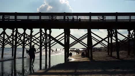 Las-Personas-Se-Ven-Recortadas-Por-Un-Sol-Poniente-En-El-Muelle-De-Folly-Beach,-Carolina-Del-Sur