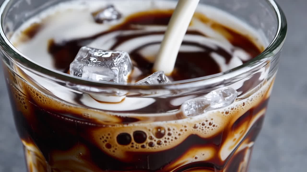 Verter leche en el café helado con cubos de hielo