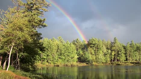 Un-Arco-Iris-Sobre-Un-Bosque-Y-Cerca-De-Un-Lago-En-La-Zona-Rural-De-Maine-1