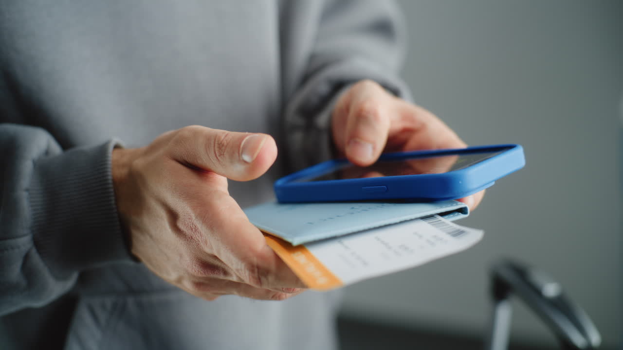persona con pasaporte, tarjeta de embarque y teléfono móvil