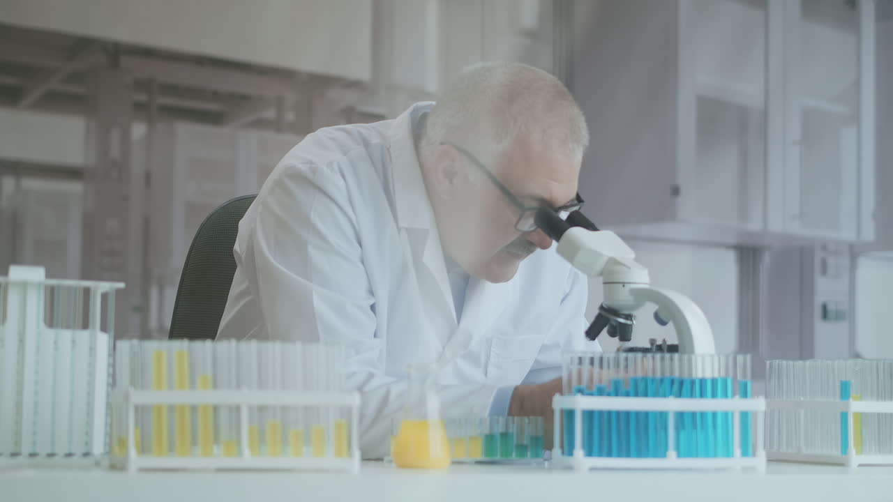 investigador caucásico barbudo con gafas de protección y trabajando con un microscopio spbas. científico usando microscopio en un laboratorio. búsqueda de vacuna contra el coronavirus. imágenes de alta calidad 4k