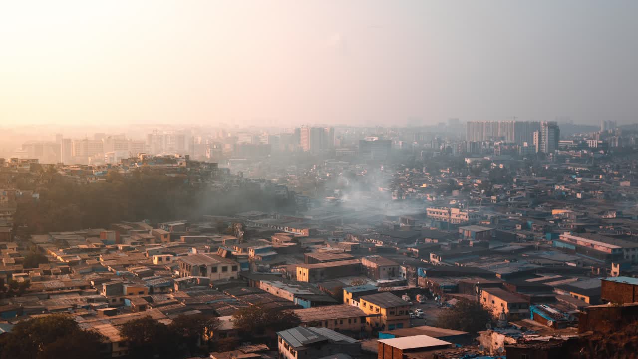 Timelapse di fumo che sale da edifici di baraccopoli al tramonto.