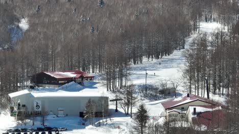 establishing shot of base of ski slopes, skiiers arriving at base of mountain where the cable car bubble cars depart from