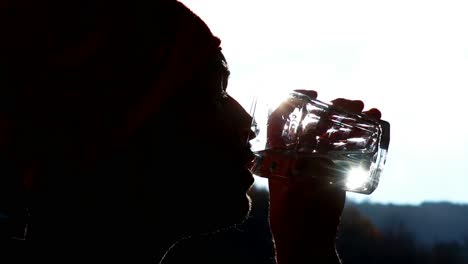 Kontrastreicher-Clip-Eines-Jungen-Kaukasischen-Mannes,-Der-Sich-Entspannt-Und-Ein-Glas-Wasser-Trinkt-–-Nahaufnahmen-Und-Aufnahmen-Bei-Gegenlicht