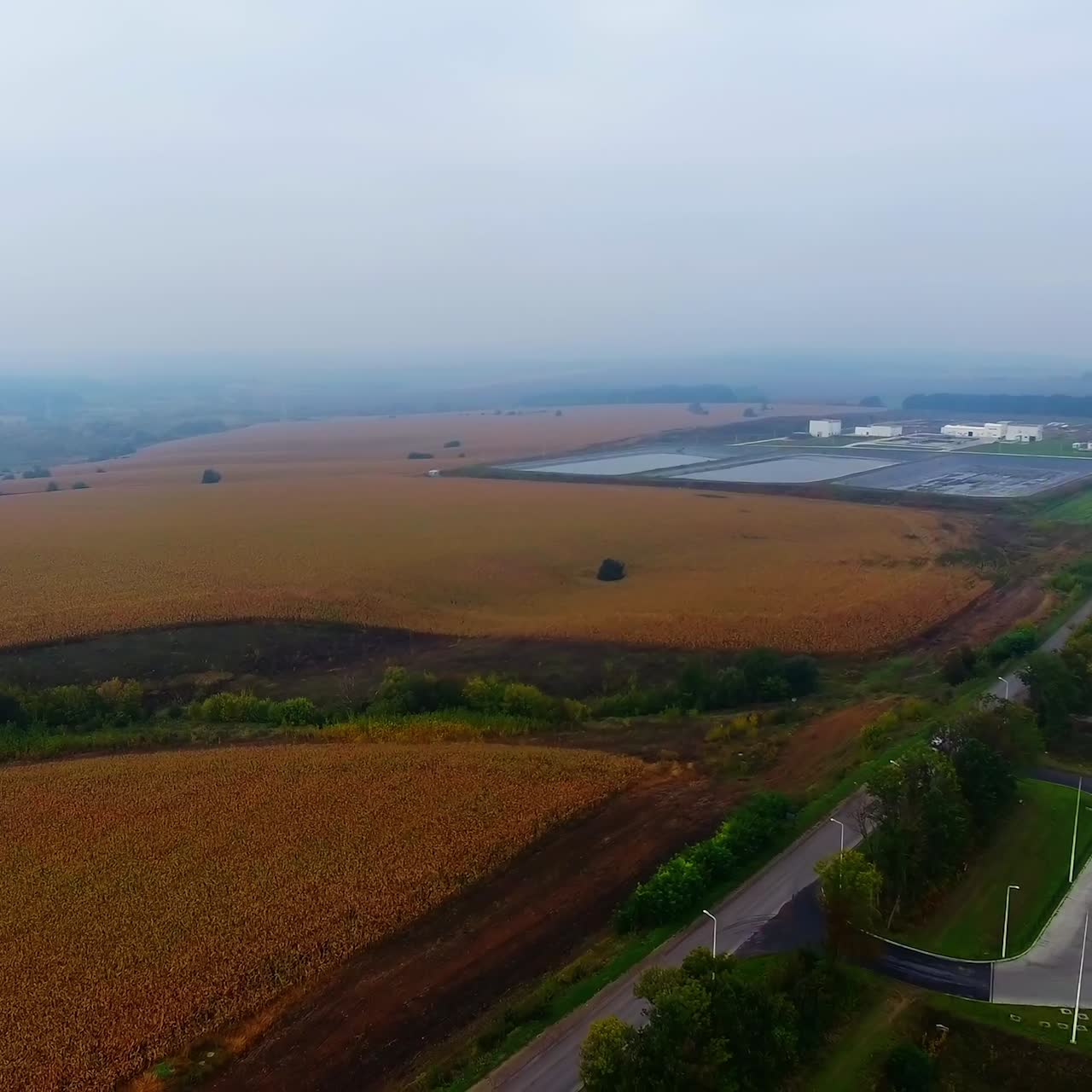 Fields in autumn. Car parking on field. Industrial zones among nature. Pollution the environment. Agricultural scenery. Aerial view.