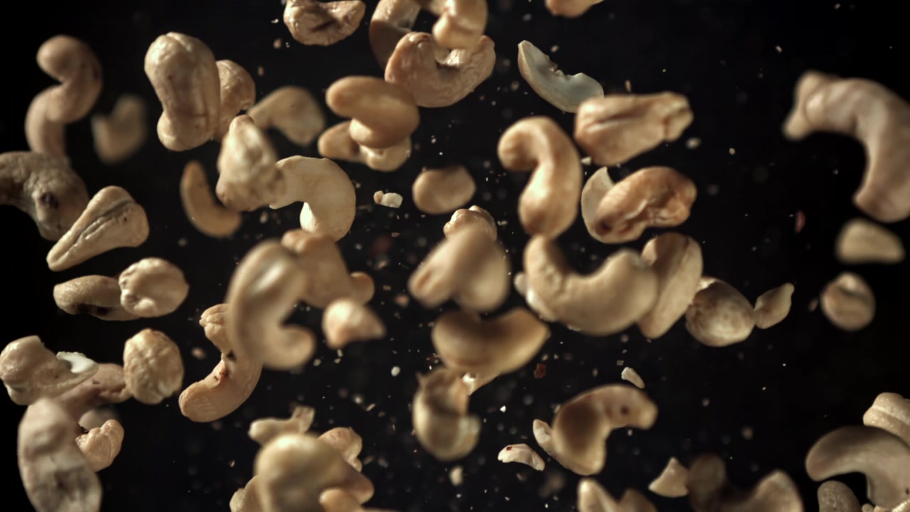 Cashewnøtter som faller i sakte film mot en svart bakgrunn