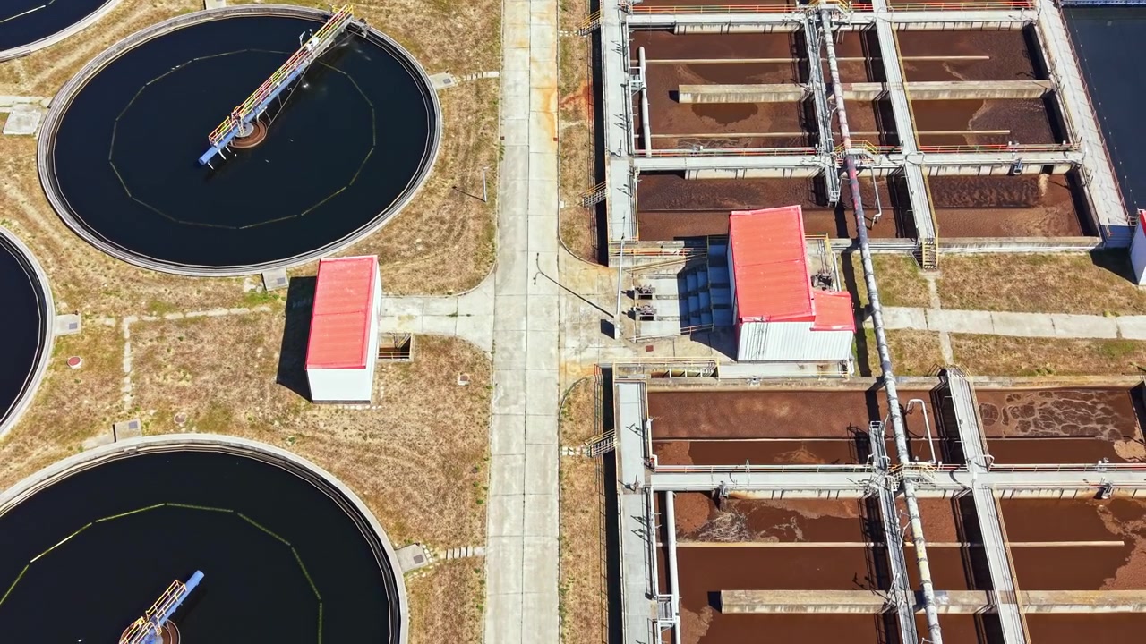 Wastewater treatment plant in operation showing various tanks and facilities during daytime