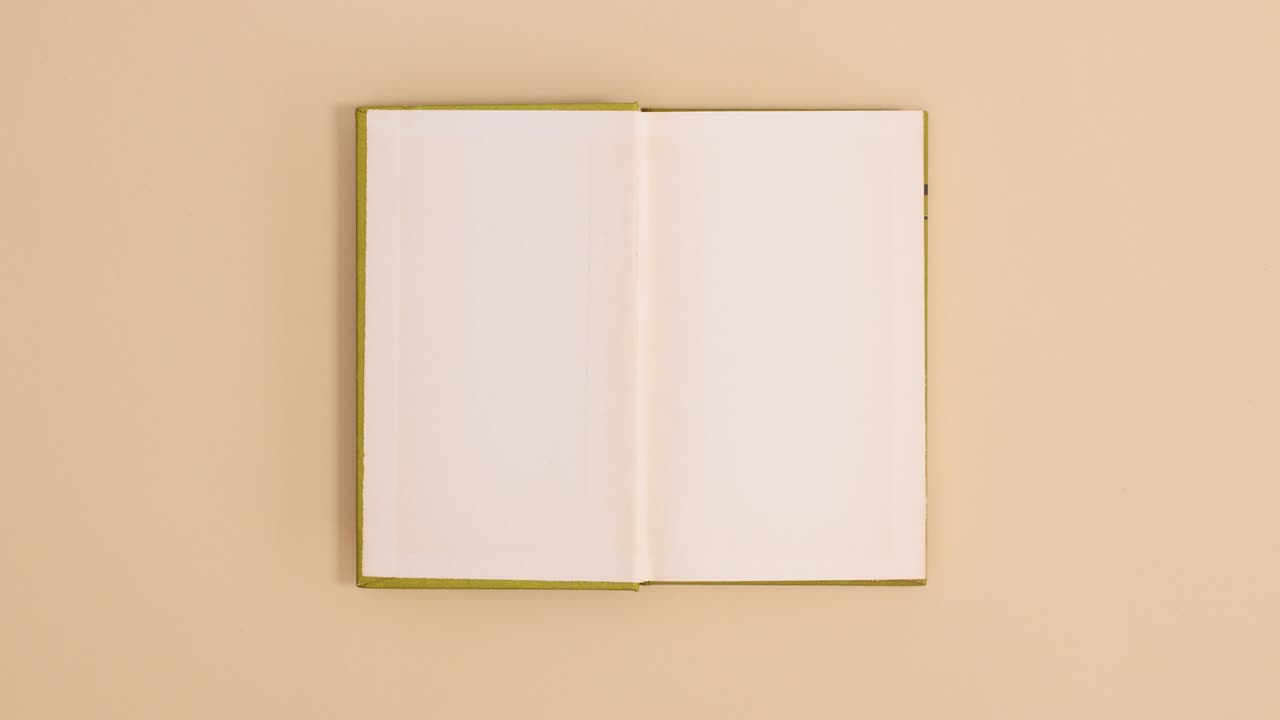 Bright green hardcover vintage book appear and open with copy space on beige background. Stop motion flat lay