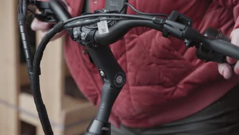 lady adjusts the bolts on the handle bar to adjust the angle of the bars before riding