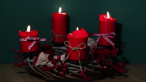 modern christmas wreath with four red candles on wooden surface with green background, holiday interior design