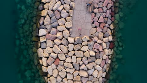 vista aérea de personas en un rompeolas transitable hecho de rocas en agua muy clara