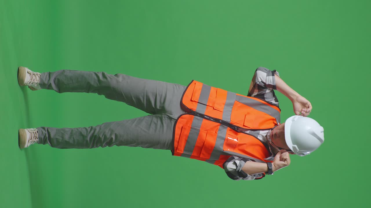 Full Body Of Asian Male Engineer With Safety Helmet Screaming Goal And Dancing Celebrating In The Green Screen Background Studio