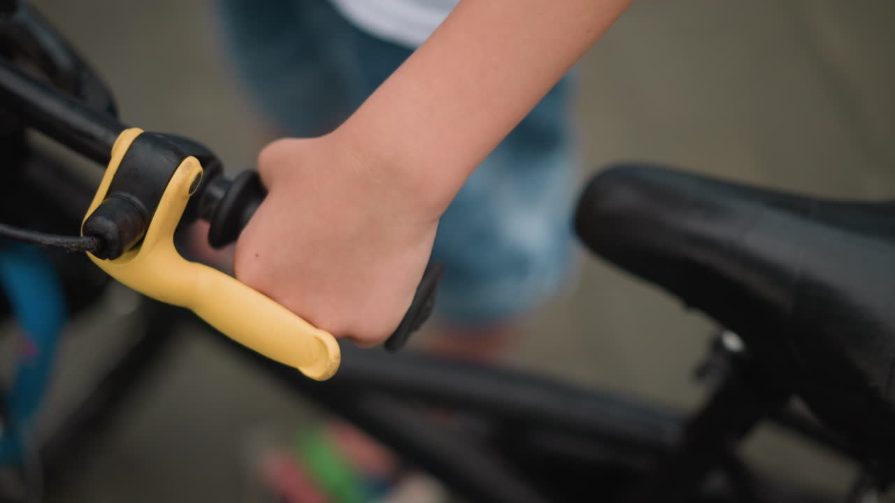 자전거의 손잡이를 잡고 있는 어린 소년의 손의 클로즈업