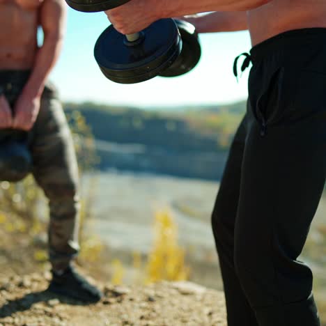 . two muscular bodybuilders. men exercising with lifting dumbbell outdoor