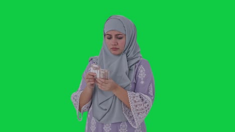 Sad-Muslim-woman-counting-money-Green-screen