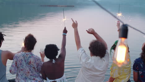 friends dancing with sparklers on lake party