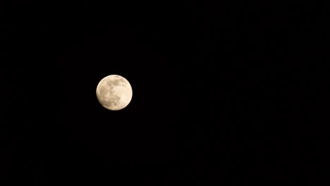 the full moon slowly moving across a clear black sky, mystical, golden glow