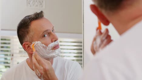 Man-shaving-his-beard-with-razor-in-bathroom-4k