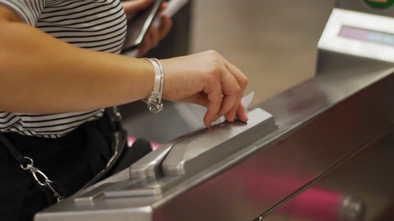 Female Hand Dragging Ticket Through Turnstile Scanner at Gate of New York Subway Station, Close Up Slow Motion