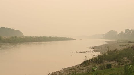 Paisaje-De-Río-Brumoso-Y-Brumoso,-Amanecer-Naranja,-Escena-Pacífica-De-Niebla-Y-Neblina-En-Un-Río-Al-Amanecer-En-Nepal-En-El-Parque-Nacional-De-Chitwan,-Escena-Tranquila-Y-Matutina-De-Paisaje-De-Río