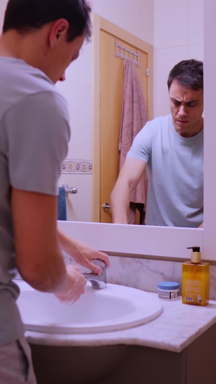 Man washing and drying hands in bathroom sink
