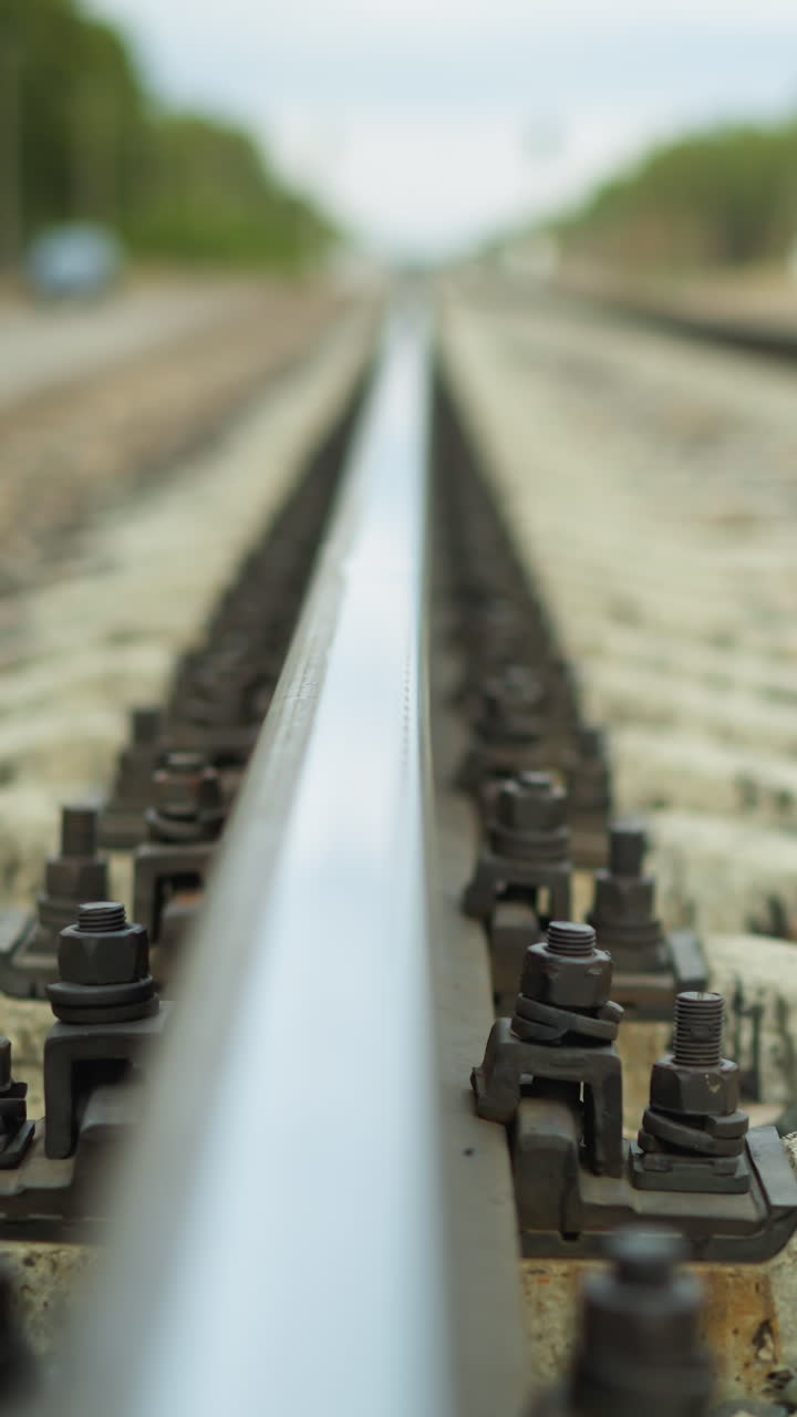 A close-up view of a railroad track stretching into the distance, the shoot focuses on the rail and its fastenings, with the background beautifully blurred, with