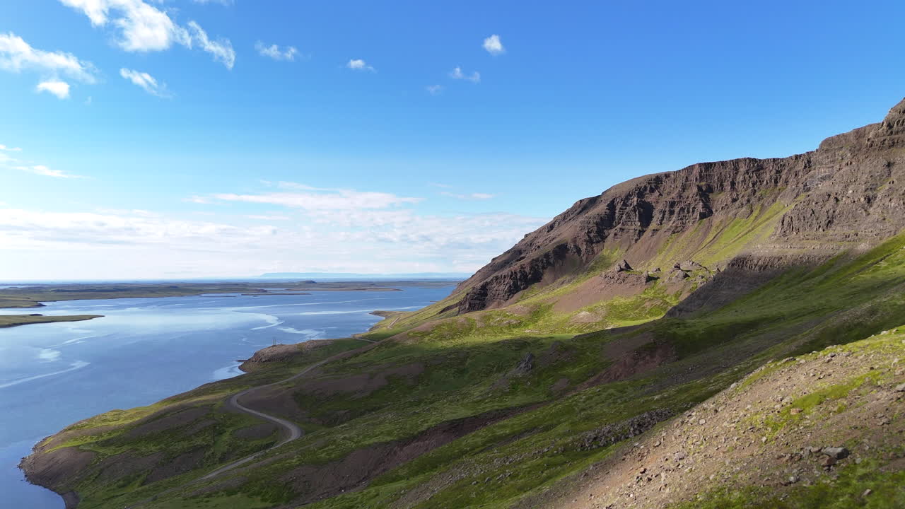 Aerial view of Hvammsfjörður in Vesturland Iceland on a colorful sunny day, showing vibrant waters, surrounding landscape, and clear blue sky from above