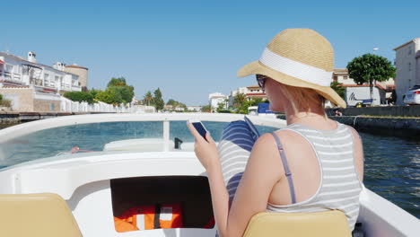 mujer siempre conectada con un teléfono en la mano en un barco que flota en el canal de la ciudad turística de e