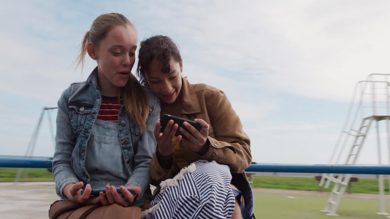Front view of a Caucasian and a mixed race girl taking selfie on a merry-go-round