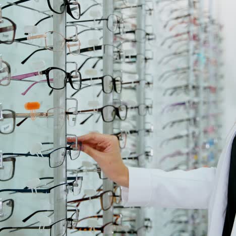 eyeglasses on the stand in the optical store. young buyer woman choosing fashionable spectacles. eyewear concept.