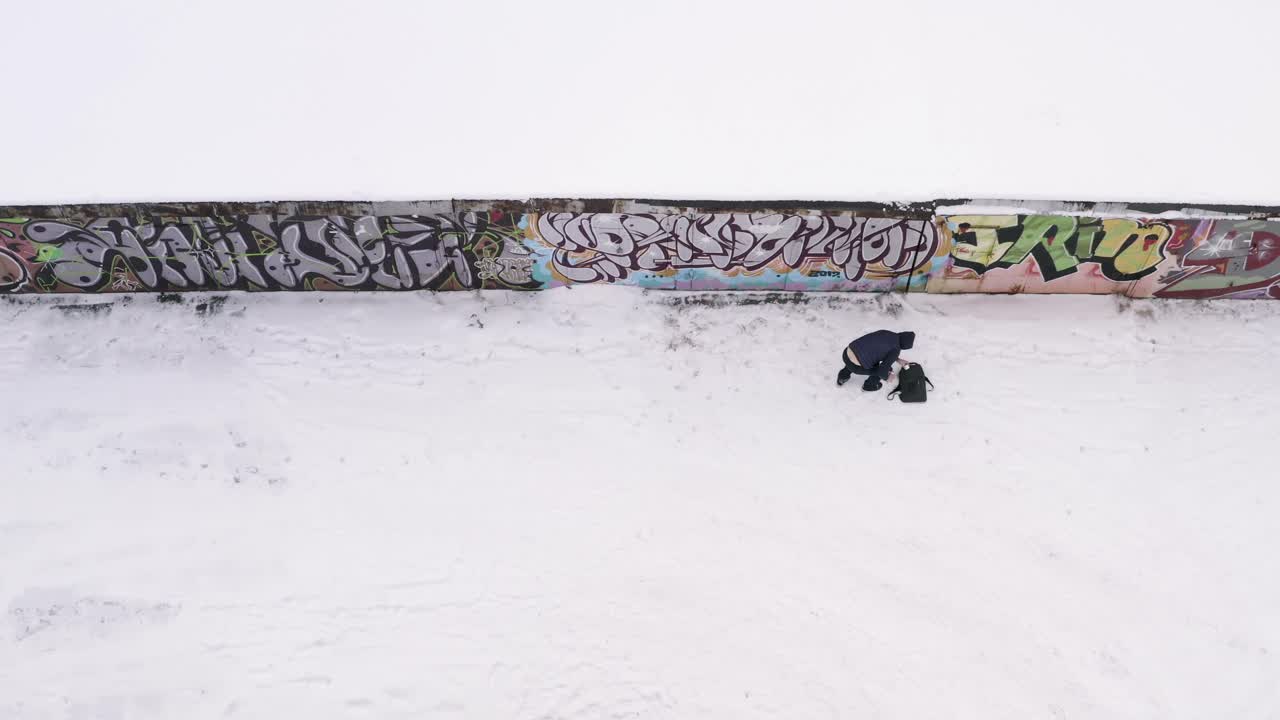 persona cerca de una pared de graffiti cubierta de nieve