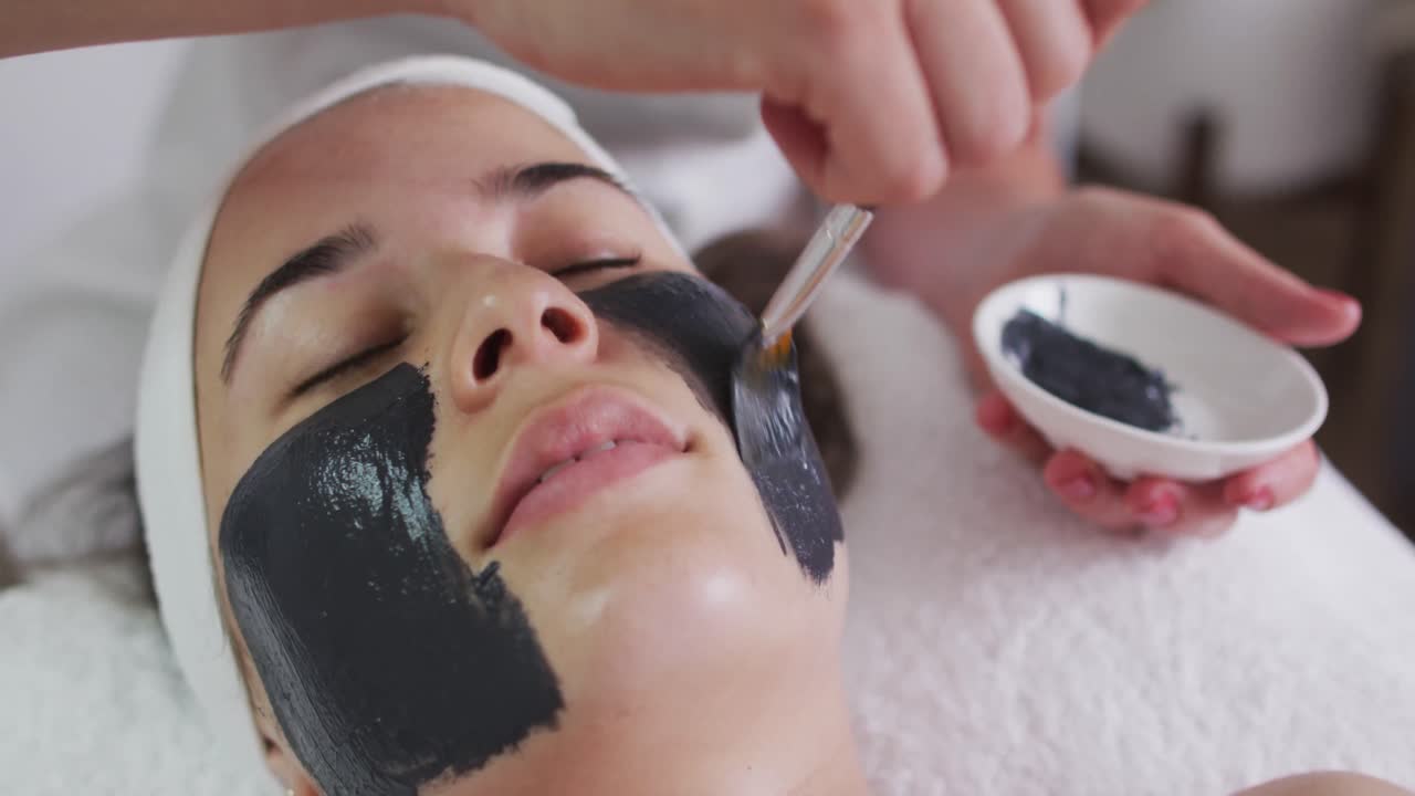 Donna caucasica distesa mentre l'estetista le applica una maschera per il viso