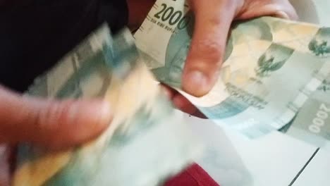 counting two thousand rupiah with indonesian money, with your east asian hand