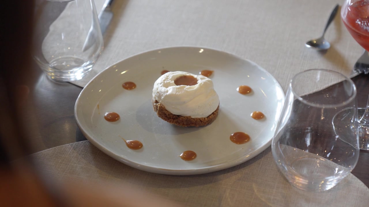 Gourmet dessert with whipped cream and caramel sauce on a white plate. Fine dining experience in a luxury restaurant.