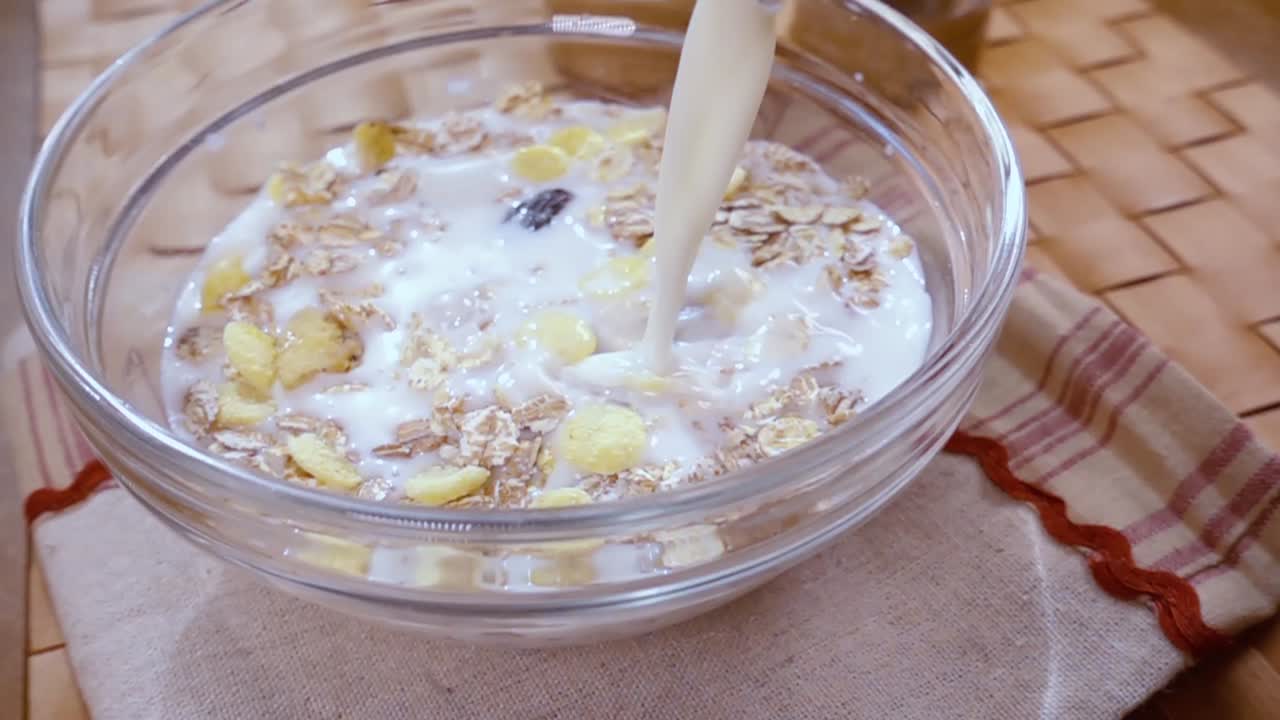 muesli de cereales de grano entero en un tazón para un delicioso desayuno matutino con leche. cámara lenta con toma de seguimiento de rotación.