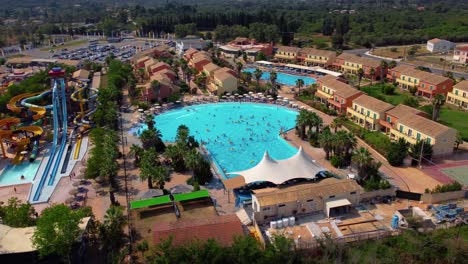 Orbiting-Drone-Shot-of-A-Busy-Water-Pool-During-a-Sunny-Summer-Day